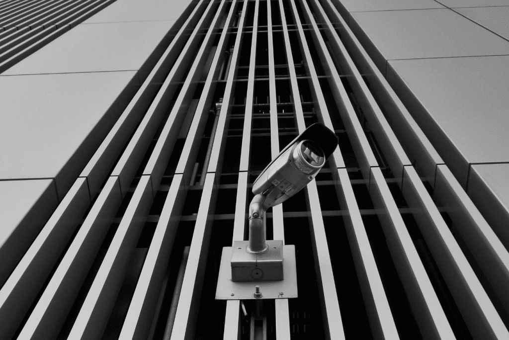Security camera on modern commercial building monitored by Stalwart Security intrusion detection systems.